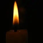 a lit candle in a dark room