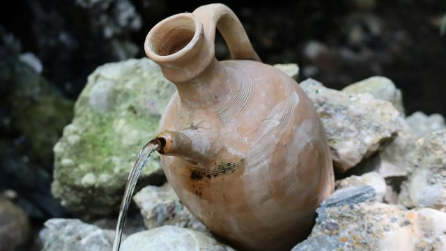 a clay jug sitting on top of a pile of rocks
