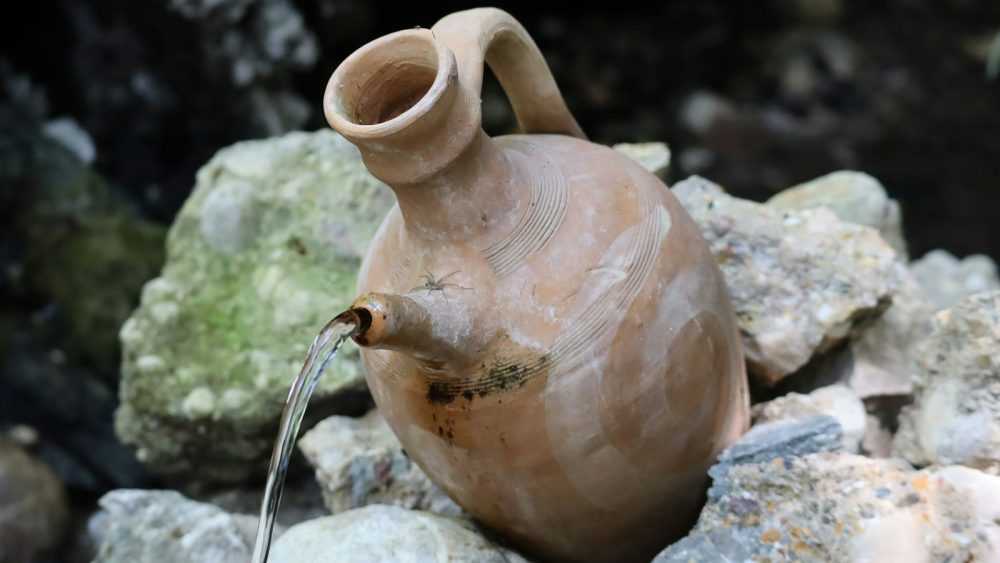 a clay jug sitting on top of a pile of rocks