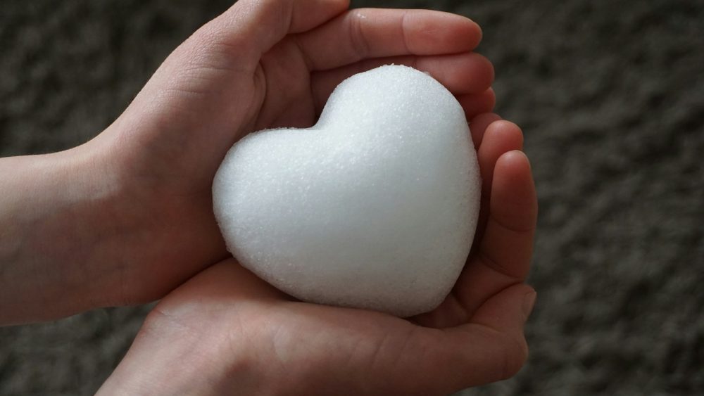a person holding a white heart in their hands